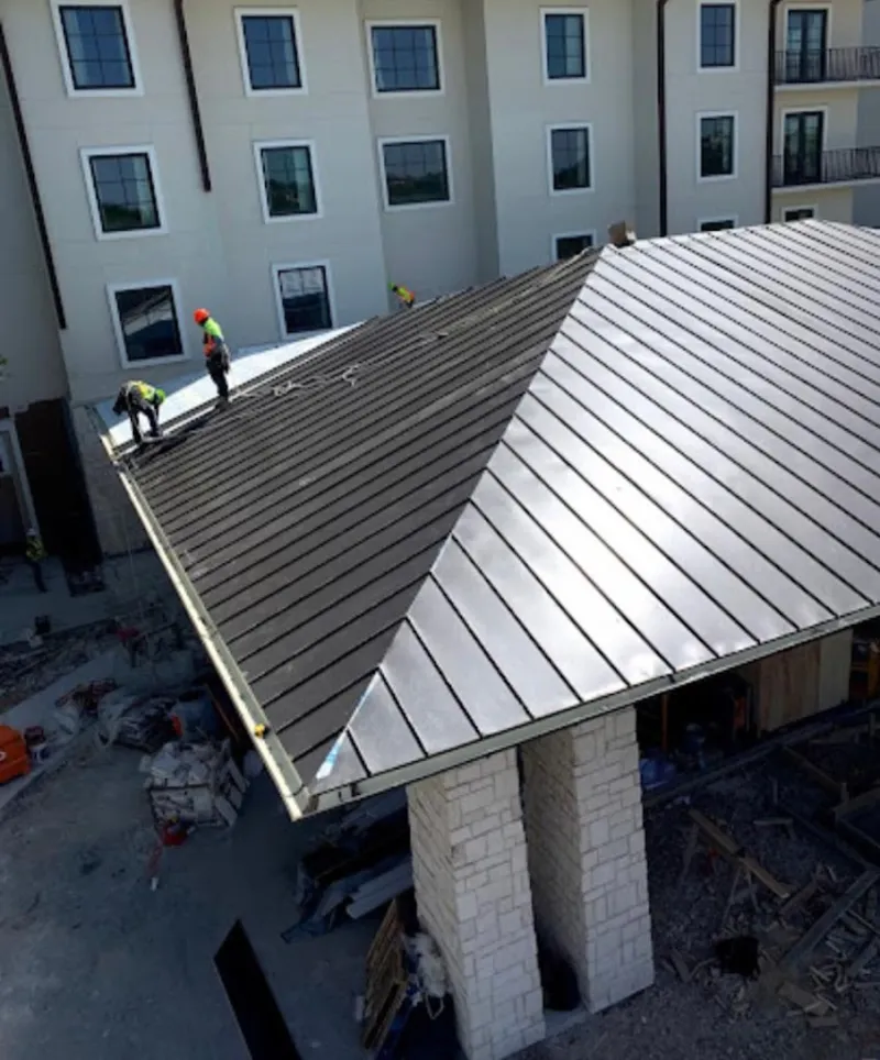 Crew installing standing seam metal roof panels on a commercial project in Ross